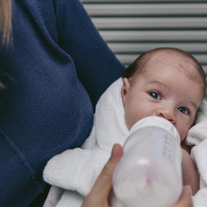 Newborn baby girl taking feeding bottle in her mother’s arms S